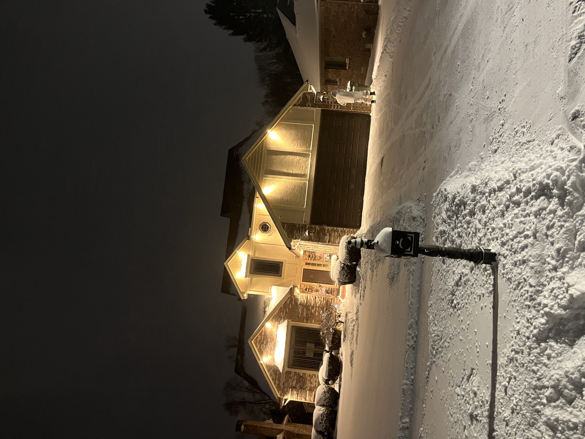 A Summit Snow and Lawn crew truck beside a freshly cleared walkway at a Macomb County home during a night snowfall