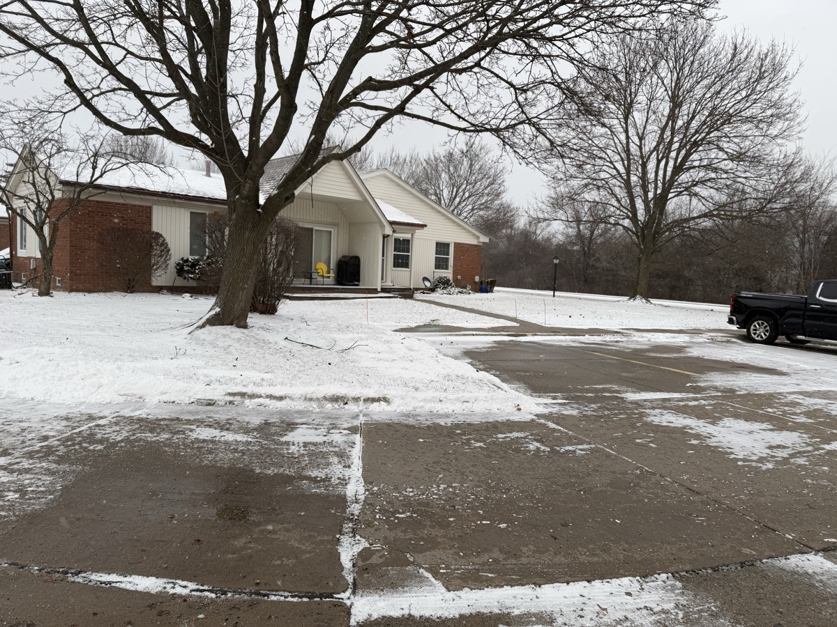 A plowed residential driveway and parking area with snow cleared to the edges in Macomb County