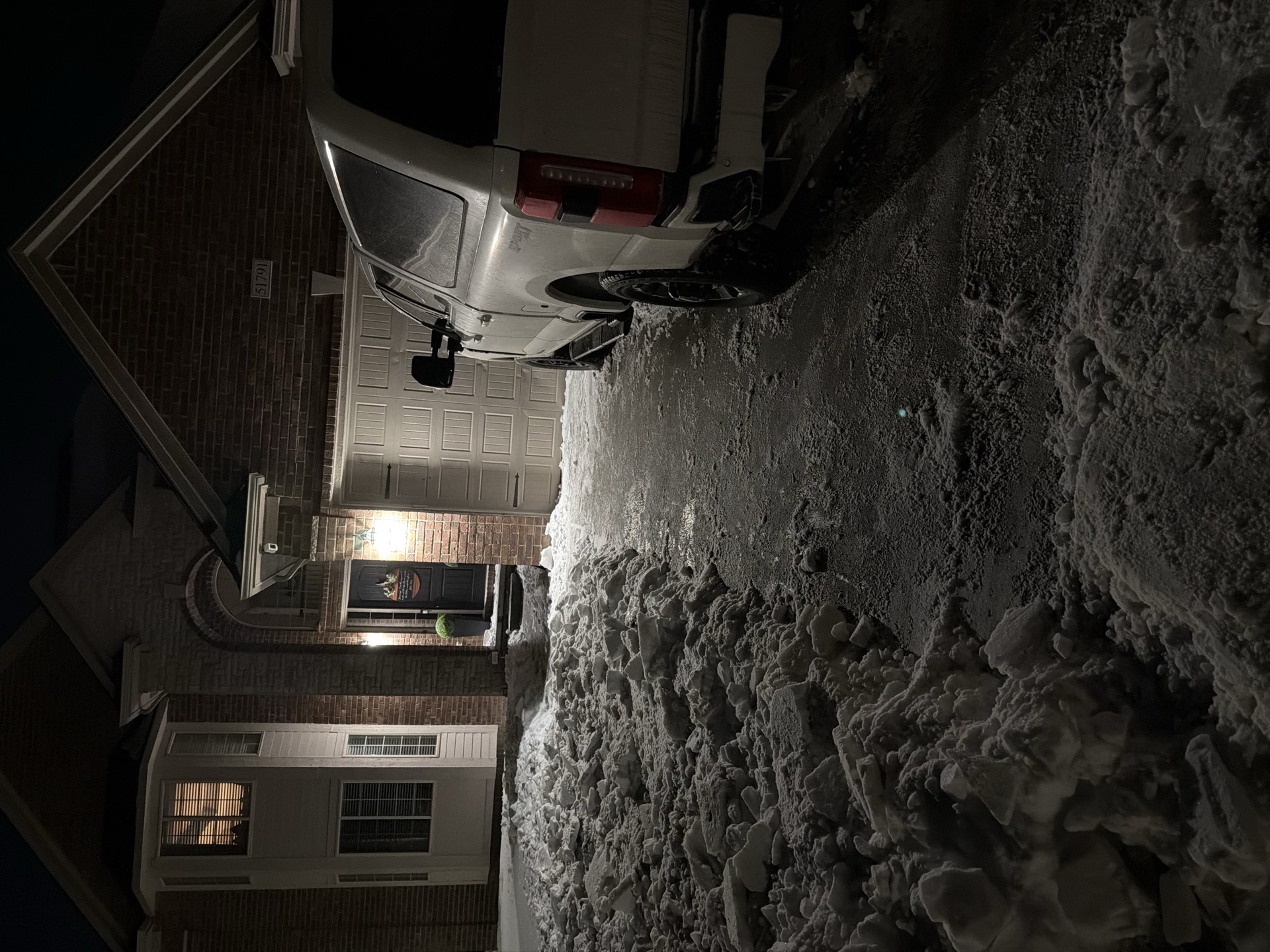 A Summit crew truck clearing a walkway during a night snowfall